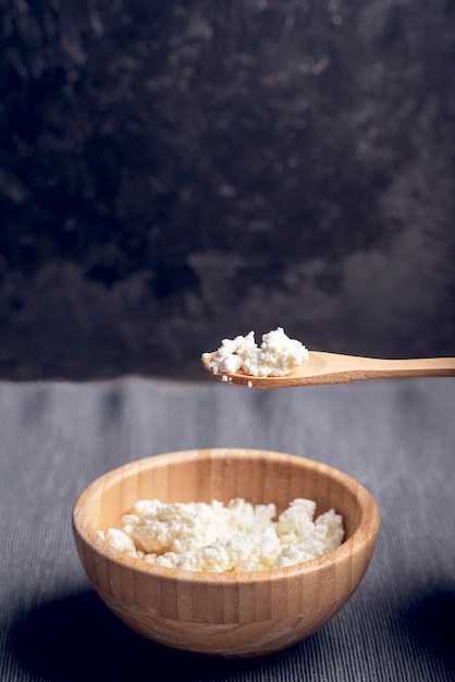 Ricotta in ciotola di legno sfondo scuro