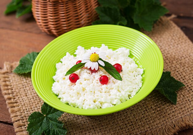 Ricotta per la colazione in una ciotola verde sul tavolo di legno. Avvicinamento