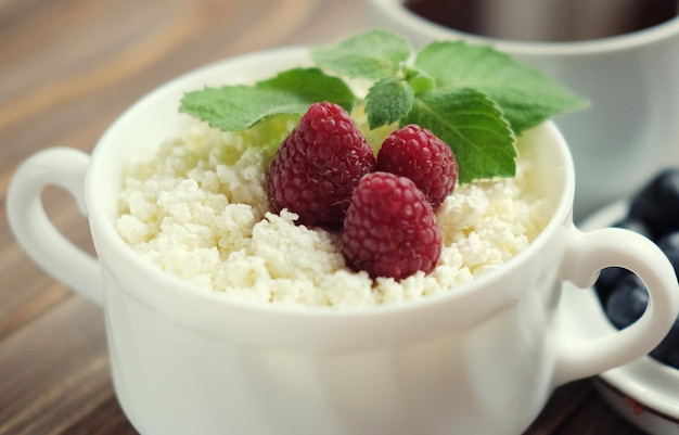 Ricotta russa con mirtilli di bacca e menta e caffè sulla tavola di legno