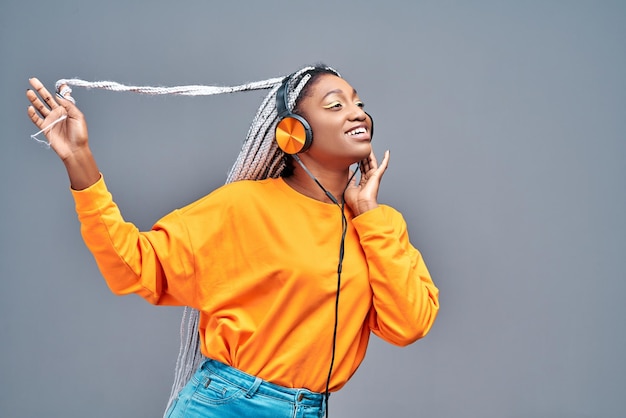 Ridendo giovane ragazza afroamericana in maglione in posa isolata su sfondo grigio ritratto in studio