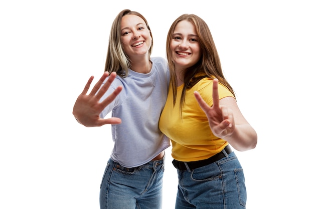 Ridere amiche in jeans. Amicizia e relazione. Isolato su uno sfondo bianco.