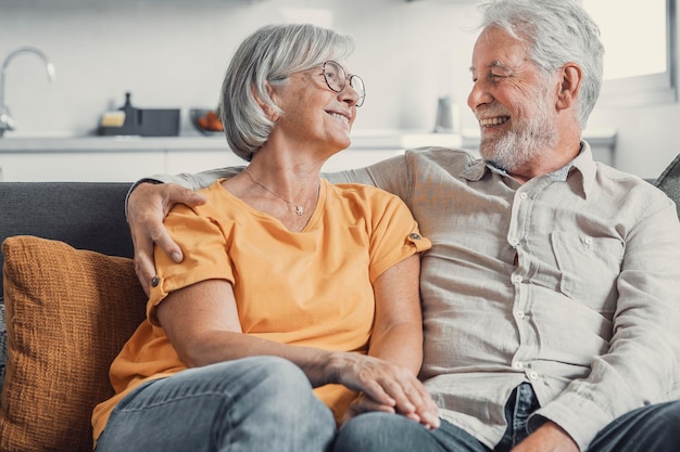 Ridere felice coppia sposata più anziana che parla ridendo in piedi nell'interno della casa insieme abbracciandosi con amore godendo di relazioni strette fiducia supporto cura sentimento gioia tenerezza