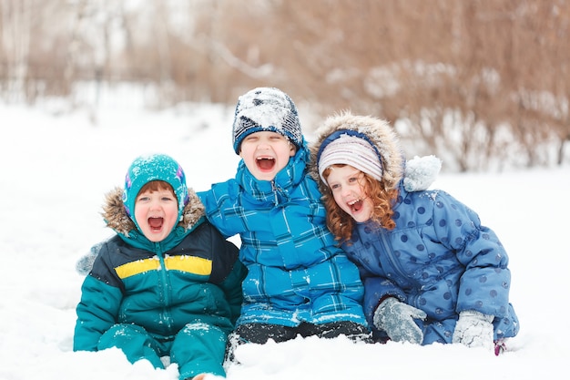 Ridere i bambini seduti su una neve.