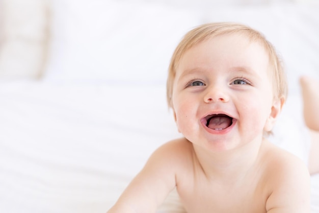 Ridere o sorridere biondo bambino con occhi grandi primo piano o ritratto in una culla a casa il concetto di articoli per bambini e accessori