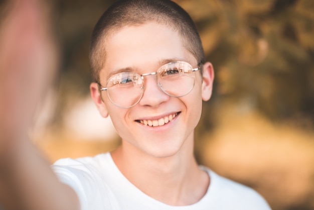 Ridere ragazzo adolescente tenendo la macchina fotografica e facendo selfie foto