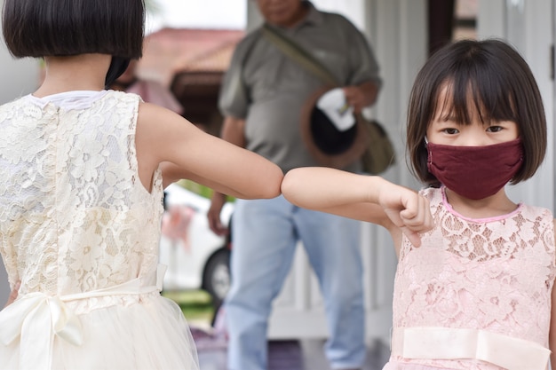 Riduzione dei contatti. Due bambini sbattono i gomiti con un nuovo saluto romanzo. Amici che manifestano per evitare la diffusione del coronavirus.