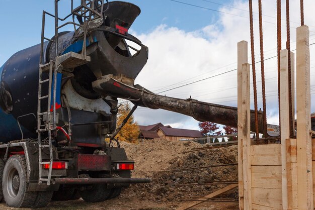 Riempimento di calcestruzzo dal miscelatore nella cassaforma in legno della fondazione