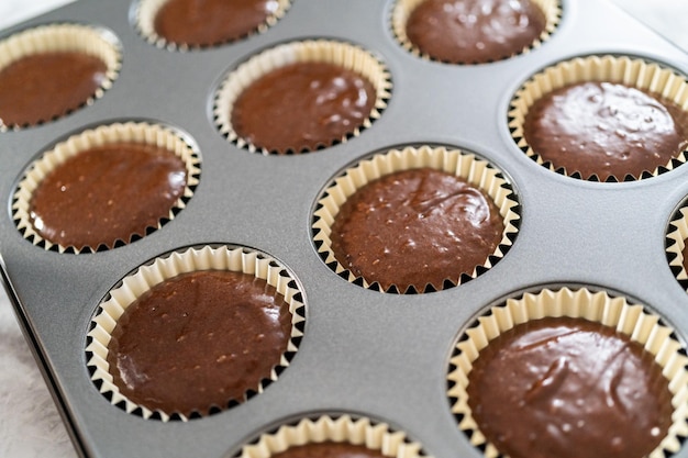 Riempire le fodere per cupcake in alluminio con una pastella per cupcake al cioccolato per cuocere i cupcake s'mores.