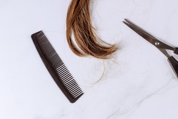 Rifinito con lunghi capelli femminili castani, forbici e pettine