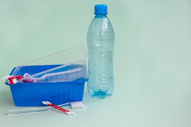 Rifiuti di plastica domestici: diversi oggetti su uno sfondo verde chiaro