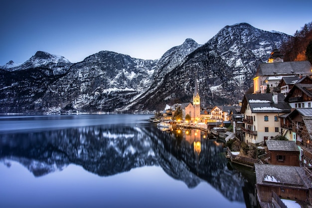 Riflessione degli edifici sulla montagna coperta di neve contro il cielo
