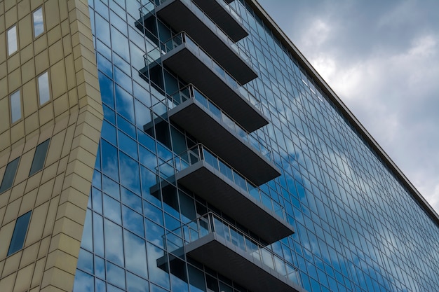 Riflessione del cielo e delle nuvole nelle finestre di un edificio di vetro a più piani.