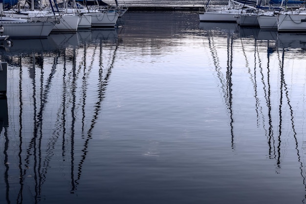 Riflessione del cielo serale e degli alberi degli yacht ormeggiati al largo del Lago di Garda in Italia