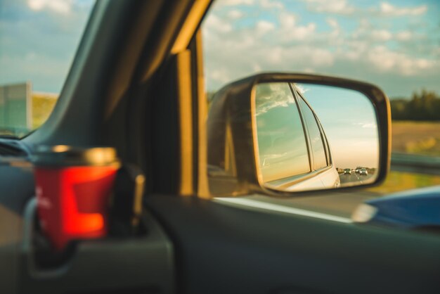 Riflessione del tramonto nello specchietto retrovisore dell'auto sull'autostrada