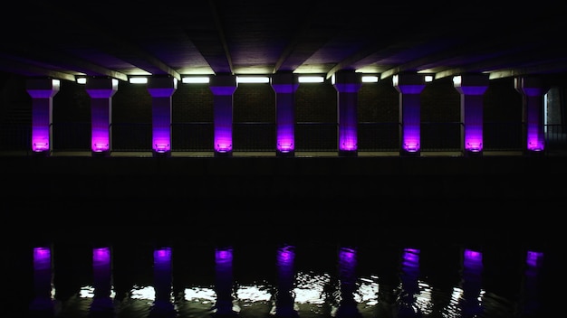 Riflessione di colonne illuminate viola nel fiume di notte