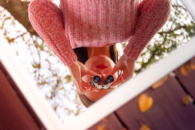 Riflesso di una donna che guarda allo specchio attraverso un binocolo