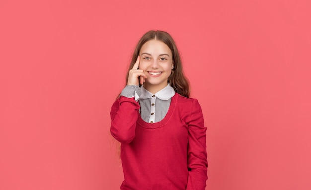 Riflettendo bambino felice in uniforme scolastica su sfondo rosso, studente.