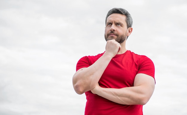 Riflettendo sull'uomo in camicia rossa all'aperto sullo sfondo del cielo