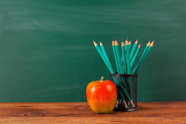 Rifornimenti di scuola su un tavolo in legno e sfondo lavagna