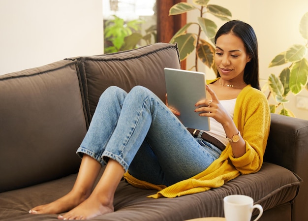 Rilassa i social media e la donna sul tablet del divano e guarda i video in salotto, pausa e rilassati Dispositivo femminile e persona sul divano lettura online e connessione a casa e ricerca su Internet