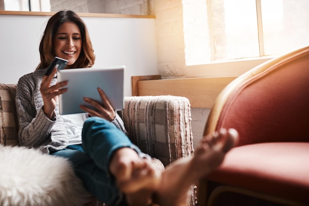 Rilassa tablet e carta di credito con una donna dell'e-commerce seduta su un divano nel soggiorno di casa sua Shopping online fintech e operazioni bancarie finanziarie con una giovane cliente online a casa sua