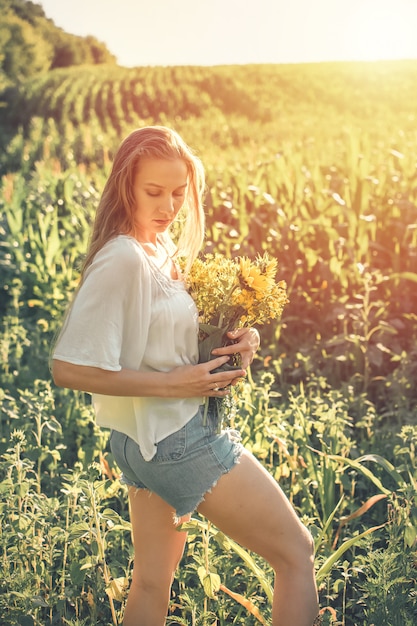 Rilassante giovane donna con abbassa in natura, in mais, campo di girasoli
