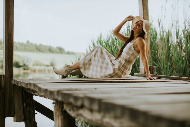 Rilassante giovane donna sul molo di legno al calmo lago