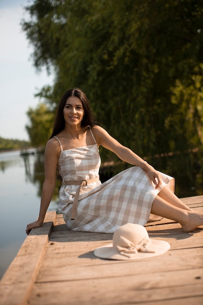 Rilassante giovane donna sul molo di legno al calmo lago