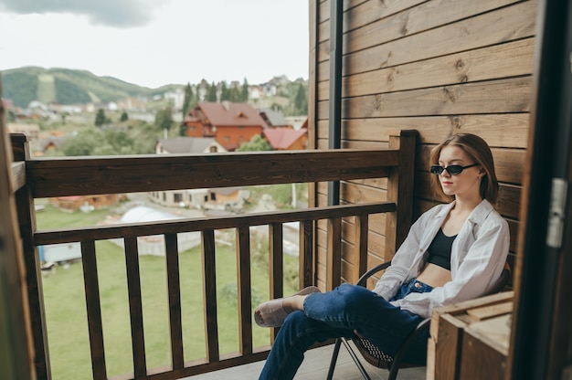 Rilassarsi al cottage, donna alla moda rilassante seduta sul balcone