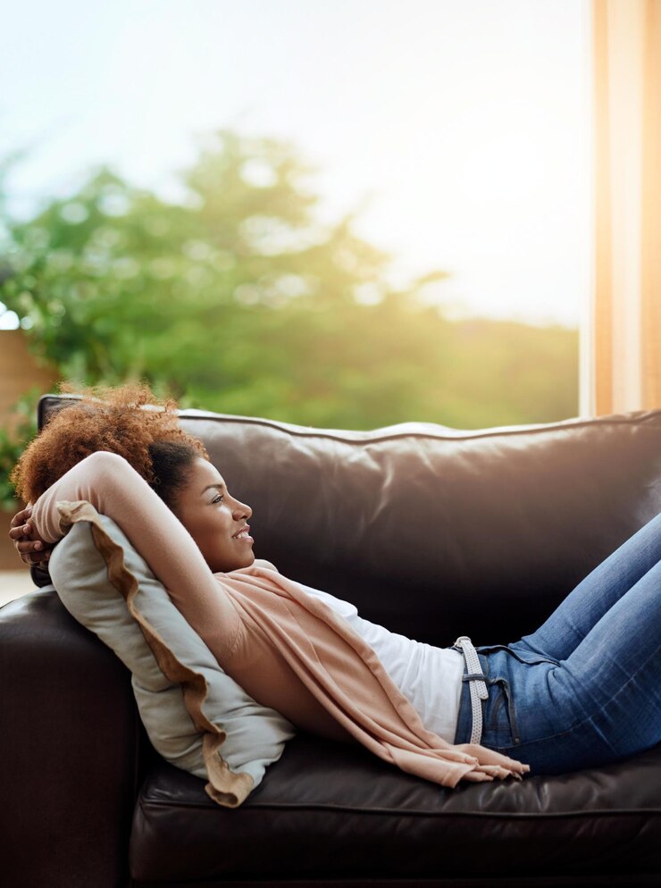 Foto rilassarsi il pensiero e la donna sul divano in casa con un sorriso stanco consapevolezza e zen mattutino nel soggiorno riposo benessere e ragazza felice sul divano con riflessione ispirazione e pace in appartamento
