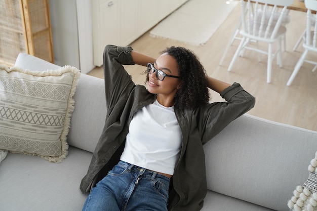 Rilassata ragazza afroamericana si siede su un comodo divano in soggiorno Benessere senza stress