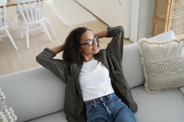 Rilassata ragazza afroamericana si siede su un comodo divano in soggiorno Benessere senza stress