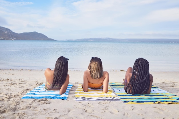 Rilassati e donne in spiaggia per le vacanze estive viaggi e legami a Bali Vacanza tropicale e amici sdraiati sulla sabbia dell'isola durante un viaggio per viaggiare tempo di qualità e una pausa