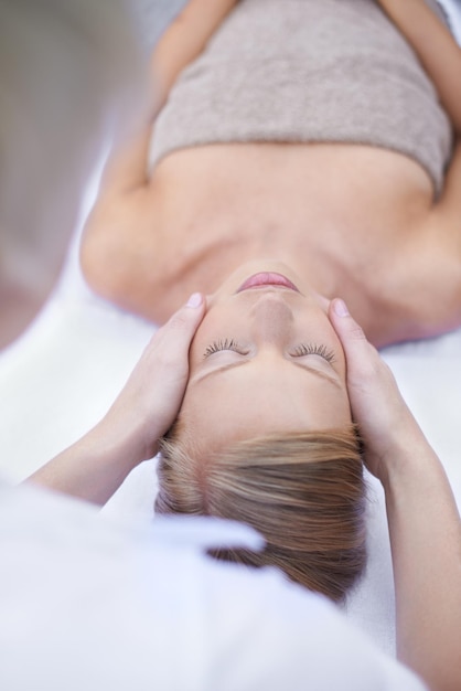 Rilassati reiki e massaggio facciale donna nella spa per la salute benessere e trattamento di lusso con gli occhi chiusi Salone di bellezza terapista professionale per la cura della pelle e volto della ragazza sul tavolo per la riflessologia