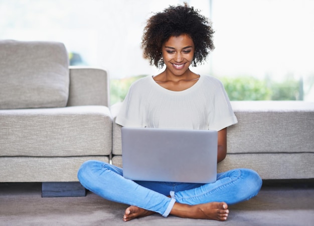 Rimanere in contatto è così facile al giorno d'oggi Foto di una giovane donna che usa un laptop mentre si rilassa a casa