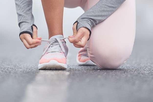 Rimani concentrato sul tuo obiettivo finale Primo piano di una persona irriconoscibile che si lega i lacci delle scarpe durante l'esercizio