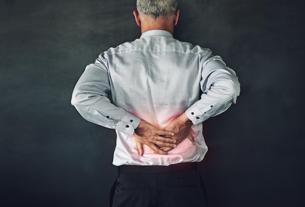 Rimette le spalle al suo lavoro. Foto in studio di un uomo maturo che soffre di tensione muscolare