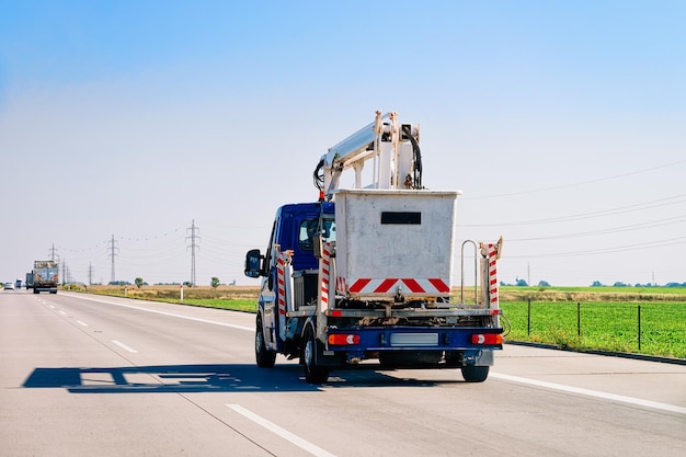 Rimorchio per il trasporto di camion con gru e contenitore per rifiuti sulla strada asfaltata in Slovenia.