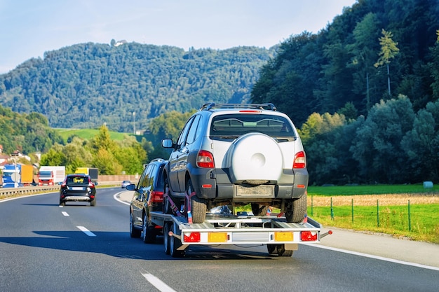 Rimorchio per trasporto auto con veicolo nuovo su strada asfaltata in Slovenia.