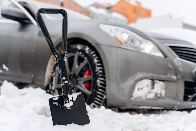 Rimozione della neve dall'auto. Pulizia auto da nevicate. Neve sulle auto dopo la nevicata. Scena urbana invernale. Auto ricoperta di neve fresca. Il processo di pulizia dell'auto dalla neve