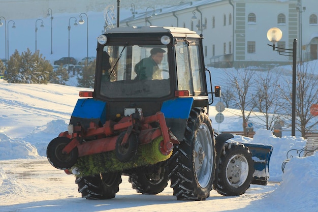 Rimozione della neve dalla strada con il trattore in città in inverno