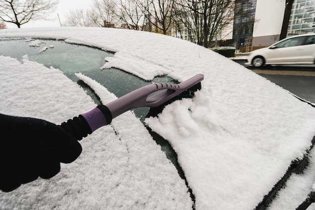 Rimuovere la neve dal finestrino dell'auto con una spazzola