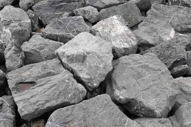 Rinforzo costiero con grandi rocce di granito grigio presso la struttura di protezione dalle inondazioni in riva al mare con