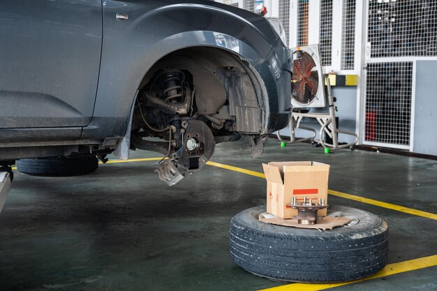 Riparare e sostituire parti di un camioncino con assale danneggiato e ruota sollevata da un sollevatore a forbice in garage