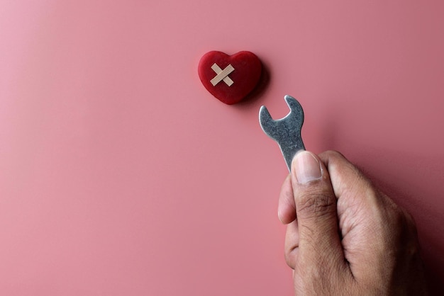 Riparare un concetto di cuore spezzato Benda rossa e chiave a cuore su sfondo rosa con spazio per la copia