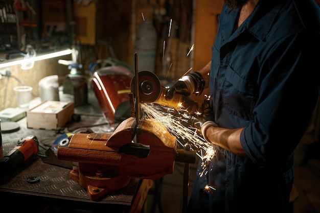 Riparatore che fa e monta pezzi di ricambio manualmente mentre lavora in officina