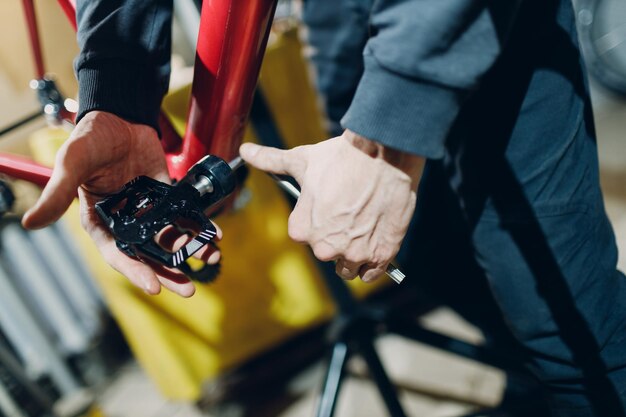 Riparatore meccanico che assembla la bicicletta personalizzata della trasmissione del pignone del pedale in officina