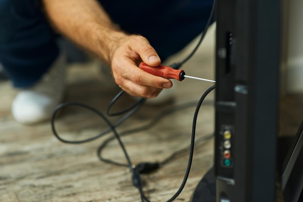 Riparazione a casa a portata di mano colpo ravvicinato della mano di un riparatore che utilizza un cacciavite durante l'installazione o