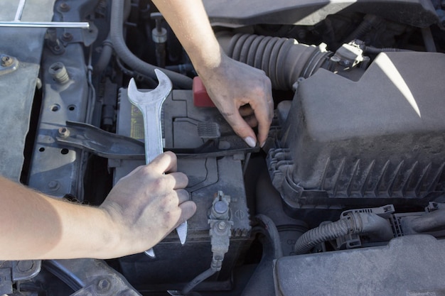Riparazione della batteria dell'auto sotto il cofano riparazione auto mani femminili