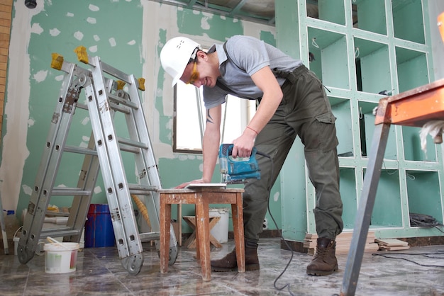 Riparazione della stanza. Edificio. Il lavoratore taglia il profilo per il muro a secco sullo sfondo del cantiere